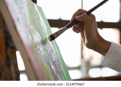 Painter hand holding paintbrush, touching canvas, putting strokes. Artist painting picture, working on artwork details at easel, drawing in art studio. Cropped close up shot, side view - Powered by Shutterstock