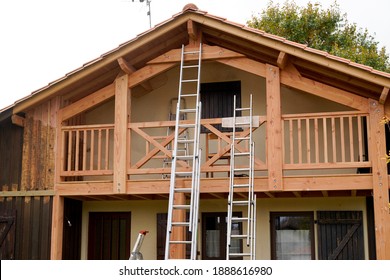 Painter Ladder Painting The Wooden Beams And Railings Of The House