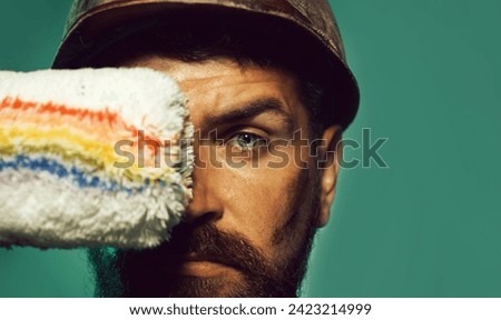 Painter man. Closeup portrait of bearded man with paint roller. Interior design, repair, home renovation and painting concept. Male painter or decorator with paintroller. Professional painter worker.