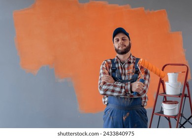 Painter man with crossed arms holding paint roller looking at camera, with natural face and confident expression. Copy space - Powered by Shutterstock