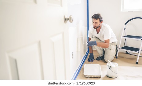 Malermann malt die Wand zu Hause, mit Malwalze und weißer Farbe. Zimmerrenovierung beim Haus.