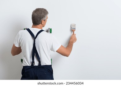 Painter On Stepladder Painting Wall With Brush