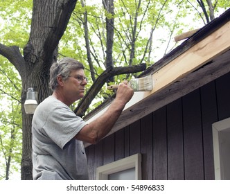 Painter Painting Trim Boards On A House