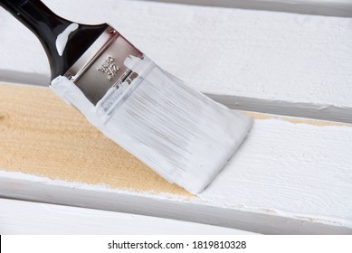 A painter primes the wooden slats of a fence that is being constructed. - Shutterstock ID 1819810328