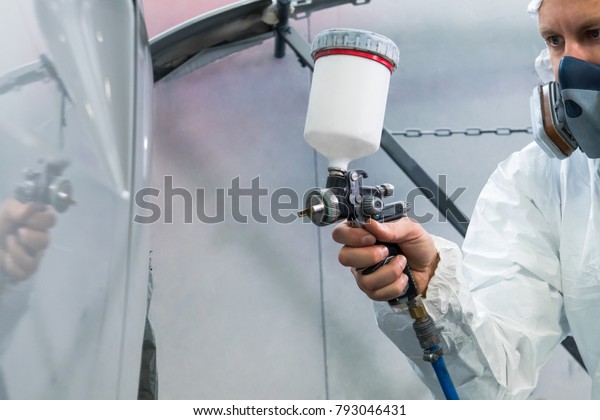 Painter spray gun in\
the hands of a painter.