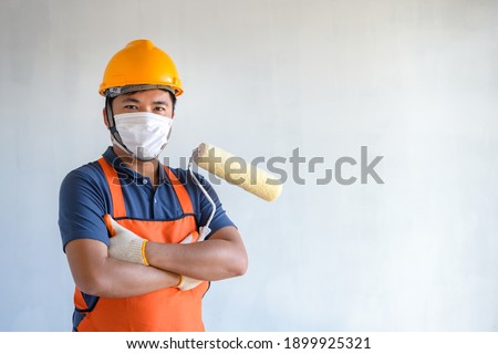 A painter wearing a protective mask Be committed to painting houses and buildings with new house paint rollers.