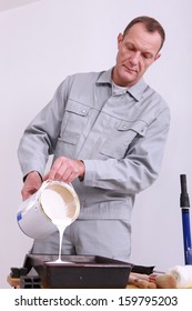 Painter At Work Pouring Paint From Can Into Tray