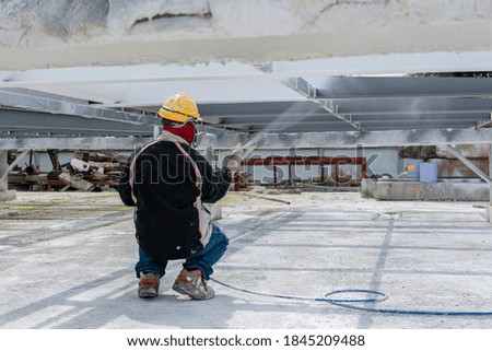 The painter is working to fireproof paint on steel structure with spray gun, at industrial factory.