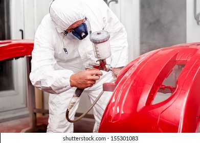 Painter Working And Painting A Red Car In Paint Garage