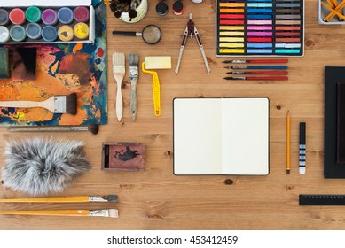 Painter workplace top view. Wooden table of an artist with art tools for drawing - Powered by Shutterstock