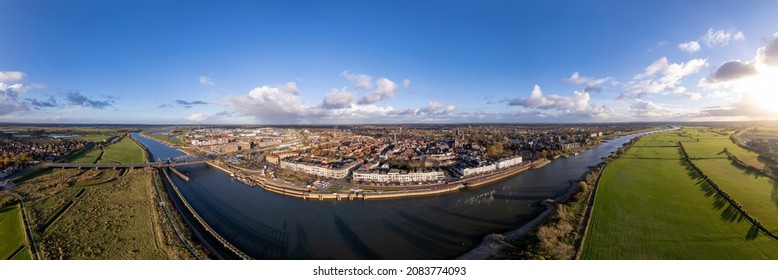 Painterly 360 panorama of Hanseatic medieval city seen from across the river IJssel passing the white countenance facades on the boulevard. Aerial cityscape of tower town Zutphen. - Shutterstock ID 2083774093