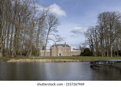 Paintero paisaje holandés con fachada exterior del castillo Slot Zeist detrás de árboles estériles de invierno en un día soleado con el parque que lo rodea y el foso