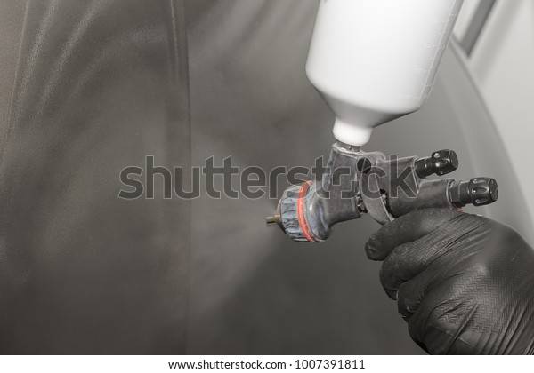 Painting of automobile parts, a man\'s hand with a\
spray gun, car body\
repair