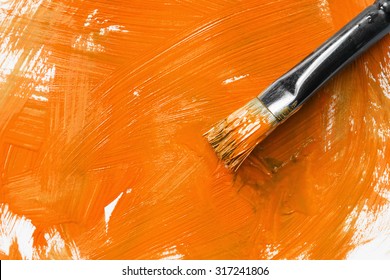 Painting Brush And Orange Paint As A Background