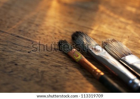 Painting brushes on an old painters desk.
