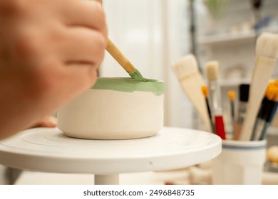 Painting ceramic products using acrylic paint and brush. Making a colorful decoration of a clay project with paint and water - Powered by Shutterstock