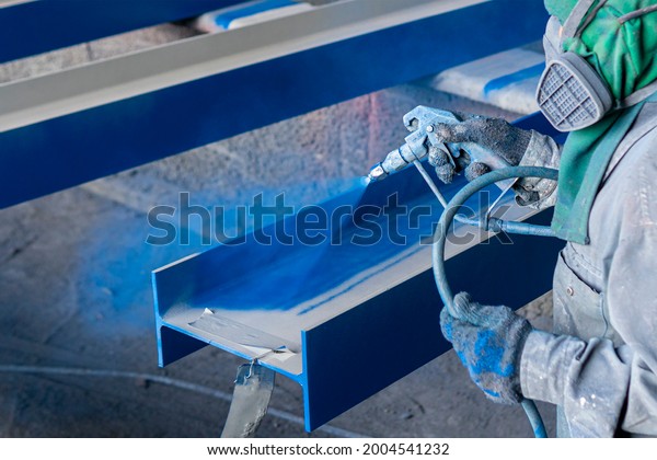 Painting color top coat on steel structure with
spray gun at industrial
factory.