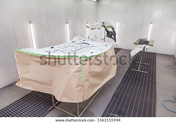 Painting and\
drying in a professional box of car body parts after applying putty\
and paint on inner side hood in the body repair shop with white\
lanterns in the working\
environment.