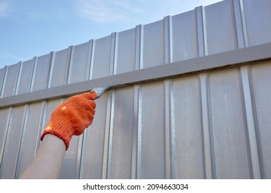 Painting the fence. Woman's hand painting steel fence with a brush - Powered by Shutterstock