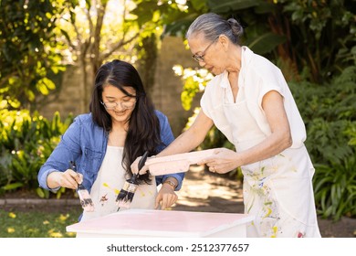 Painting furniture together, asian grandmother and granddaughter enjoying outdoor activity. Family, bonding, DIY, teamwork, multigenerational, hands-on - Powered by Shutterstock