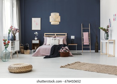 Painting Hanging On Dark Blue Wall In Cozy Bedroom With Fresh Flowers