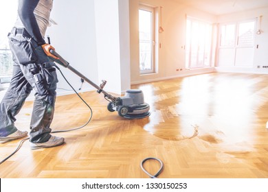 Painting or oiling of oak parquet, worker with polishing tool herringbone parquet