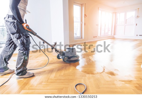 Painting or oiling of oak parquet, worker with\
polishing tool herringbone\
parquet
