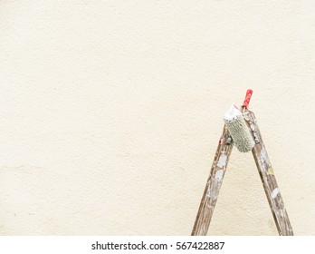 Painting outdoor walls with ladder and roller during renovation.