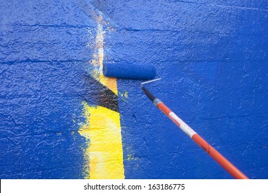 Painting Over Graffiti On A Wall With A Paint Roller