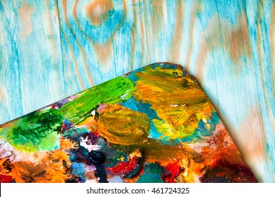 Painting palette on colored wooden background