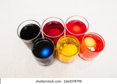 Painting process of Easter eggs by dye in the glasses. Home decorations for the holiday. Close-up.