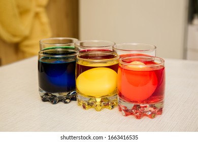 Painting process of Easter eggs by dye in the glasses. Home decorations for the holiday. Close-up.