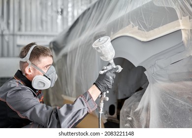 Painting the rear part of the car. Car painter wearing costume and protective gear. Car service station. Restoring a car after an accident - Powered by Shutterstock