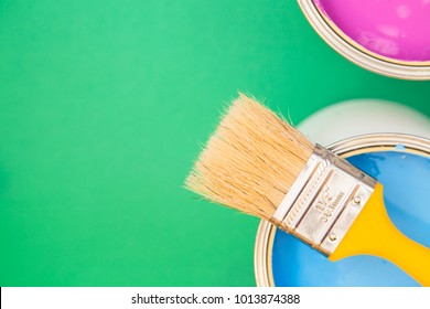 Painting, Redecorating House Concept. Tin Can Of Blue Oil Paint With A Brush, Green Background With Copy Space, Top View, Flat Lay