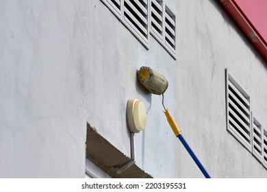 Painting The Street Wall With A Roller With Gray Paint