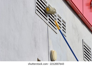 Painting The Street Wall With A Roller With Gray Paint