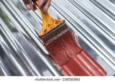 Painting the surface of a sheet of Galvanized Iron or GI corrugated metal with rust inhibiting red oxide primer. - Shutterstock ID 2180365861