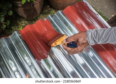 Painting the surface of a sheet of Galvanized Iron or GI corrugated metal with rust inhibiting red oxide primer. - Shutterstock ID 2180365869