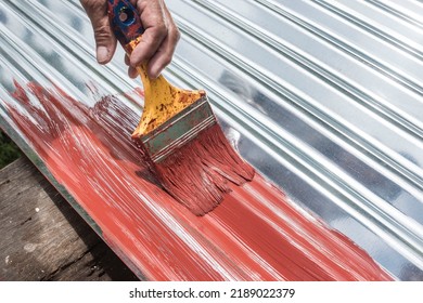Painting the surface of a sheet of Galvanized Iron or GI corrugated metal with rust inhibiting red oxide primer. - Shutterstock ID 2189022379