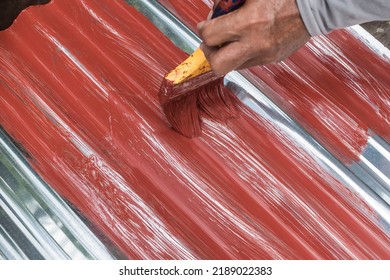 Painting the surface of a sheet of Galvanized Iron or GI corrugated metal with rust inhibiting red oxide primer. - Shutterstock ID 2189022383