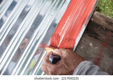 Painting the surface of a sheet of Galvanized Iron or GI corrugated metal with rust inhibiting red oxide primer. - Shutterstock ID 2217043235