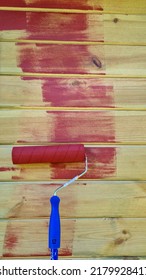 Painting The Wall Of A Wooden Garden House With A Roller In Red In Summer