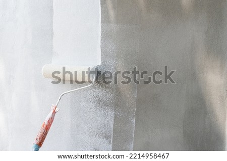 Painting of walls in a white color. Close-up house paint roller, home improvements, horizontal view with copy space.