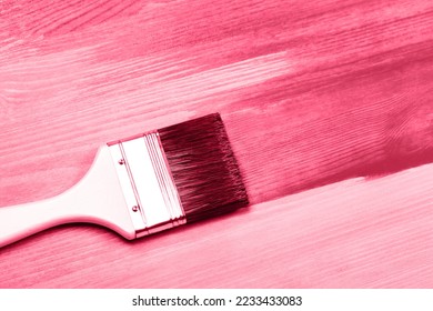 Painting white wooden surface with white paintbrush and red color color. Demonstrating Viva Magenta - trendy color of the year 2023 - Shutterstock ID 2233433083