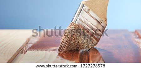Painting wooden floor with protective varnish on a blue background. Photo from copy space.