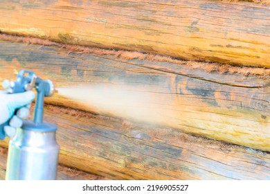 Painting A Wooden House With A Compressor And Paint Sprayer. High Quality Photo