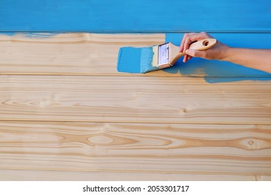 Painting a wooden wall. Brush in the woman's hand. Blue paint on wood. - Powered by Shutterstock