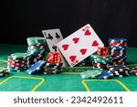 A pair of aces and stack of chips on casino green table.