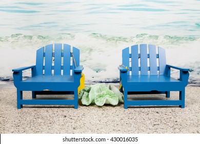 A Pair Of Adirondack Chairs Sitting On The Beach