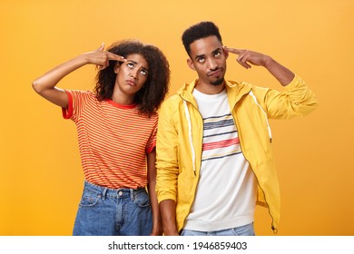 Pair Of African American Lovers Getting Annoyed With Parents Scolding, Teaching Them How Live Sexual Life Rolling Eyes Up From Irritation Holding Finger Gun Near Temples Standing Close To Each Other